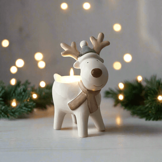 Tealight Holder Reindeer with Hat and Scarf.Add a touch of festive cheer to your home with this charming ceramic reindeer tealight holder. Its simplistic design, featuring neutral tones and a bold cute red nose, makes it a versatile piece that complements