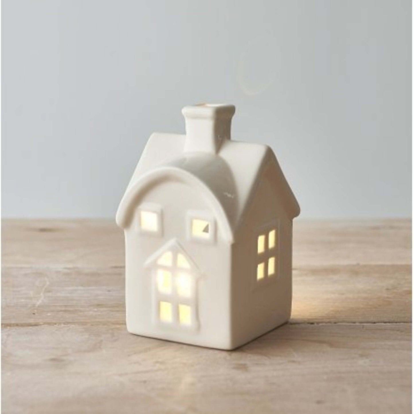 White Ceramic House T-light Holder with Heart Decal. Add a touch of whimsy to your holiday decor. This adorable white ceramic house tealight holder, featuring a charming cut-out heart decal, is the perfect way to bring a touch of festive cheer to your hom