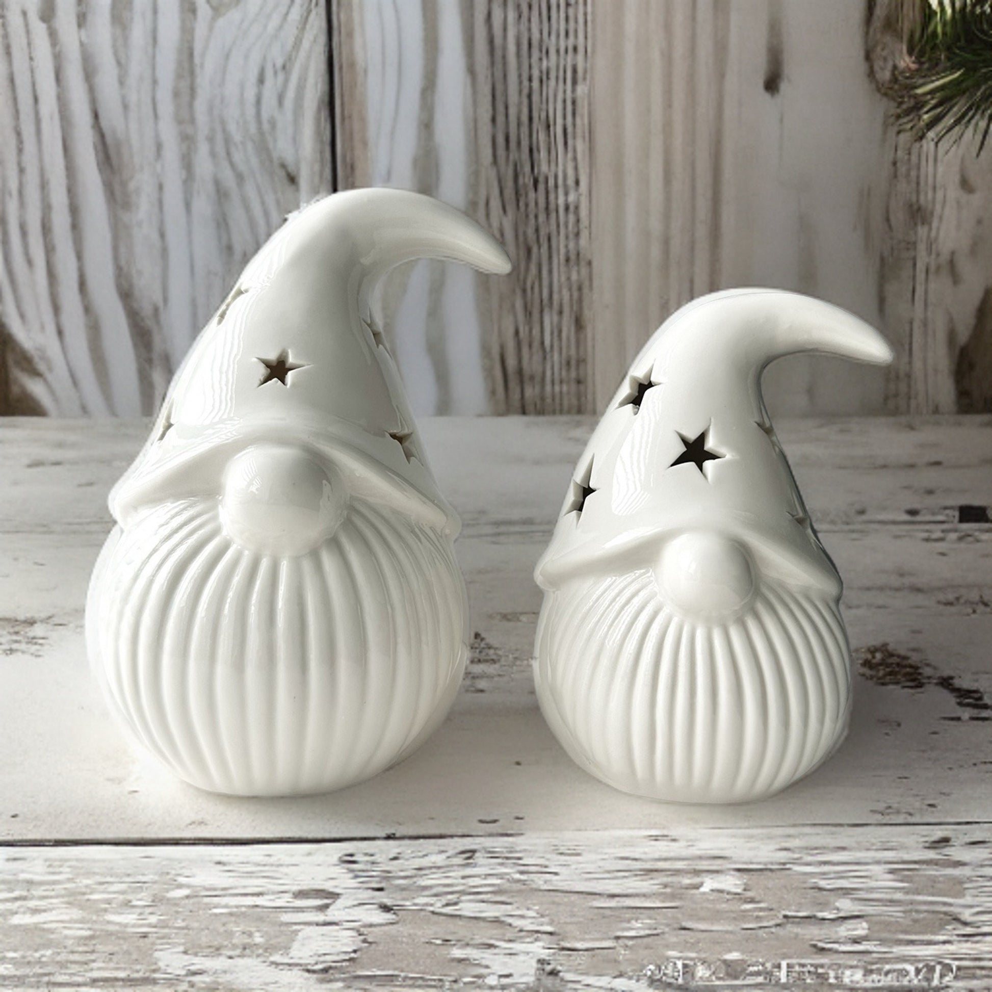 White Porcelain Light-Up Gonks - Add a touch of whimsy and festive cheer to your home with this adorable set of 2 white porcelain gonks. These charming gnomes, each featuring a star cut-out decal on their hats and LED lights, are the perfect way to brigh