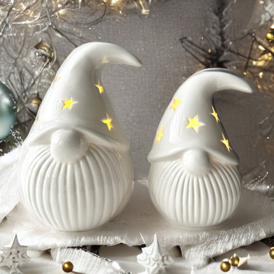 White Porcelain Light-Up Gonks - Add a touch of whimsy and festive cheer to your home with this adorable set of 2 white porcelain gonks. These charming gnomes, each featuring a star cut-out decal on their hats and LED lights, are the perfect way to brigh